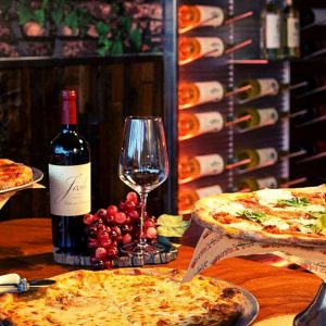 A table at a wine club pizza restaurant in Pompano Beach with a wine rack in the background